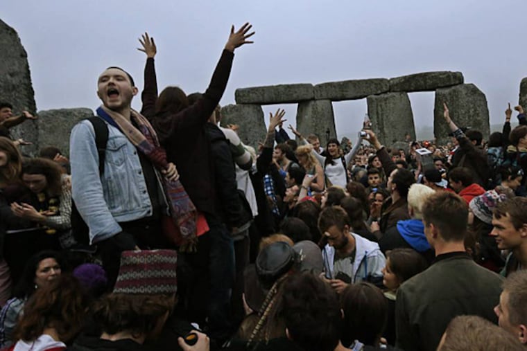 People raise their hands in celebration during the summer solstice shortly after 4:52 am at the prehistoric Stonehenge monument, near Salisbury, England, Friday, June 21, 2013. Following an annual all-night party, thousands of New Agers and neo-pagans danced and whooped in delight at the ancient stone circle Stonehenge, marking the summer solstice, the longest day of the year. (AP Photo/Lefteris Pitarakis)