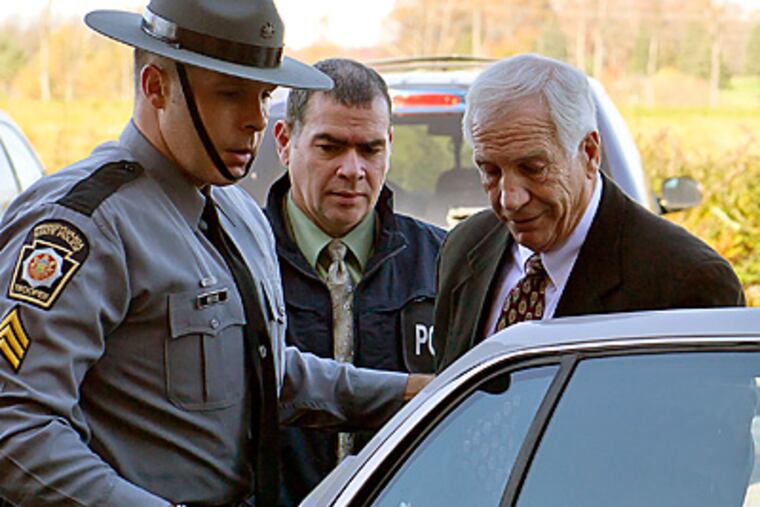 Former Penn State assistant Jerry Sandusky is put in the back of a police car. (AP Photo/The Patriot-News, Andy Colwell)