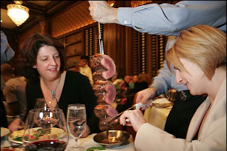A waiter/gaucho slices meat at the table.