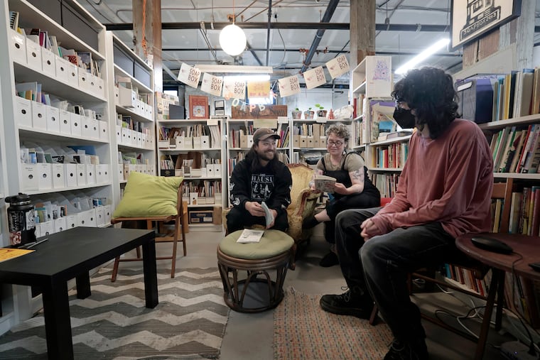 The zine library at the Soapbox, a West Philly community print shop. Studio coordinator Matao Dreskin (from left), board president Karen Lowry, and fellow Belle Handler sit among the zines.