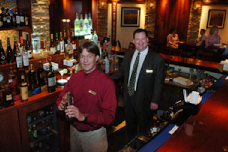 Bartender Fred Silhol and assistant director of food and beverage Jerry McConway Jr. in the new Embers Wood Fired Grill at the former Hilton.