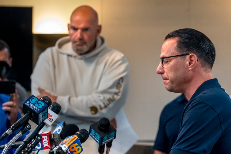 U.S. Sen. John Fetterman (left) looks on as Gov. Josh Shapiro speaks during a news media update at the Upper Makefield police headquarters in 2023, following a fatal flash flooding. Fetterman's new memoir details their tense relationship.