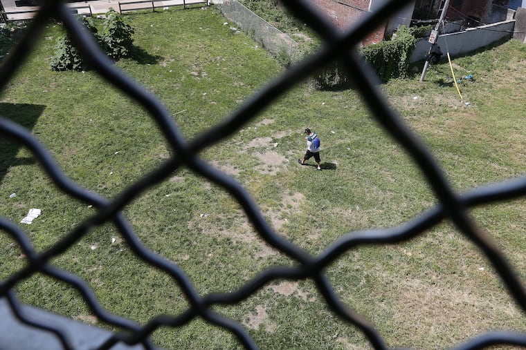 A man walks through a lot at Somerset and Kensington Avenue, near where an unknown man was found in a trash littered alley in December, dead from an overdose.