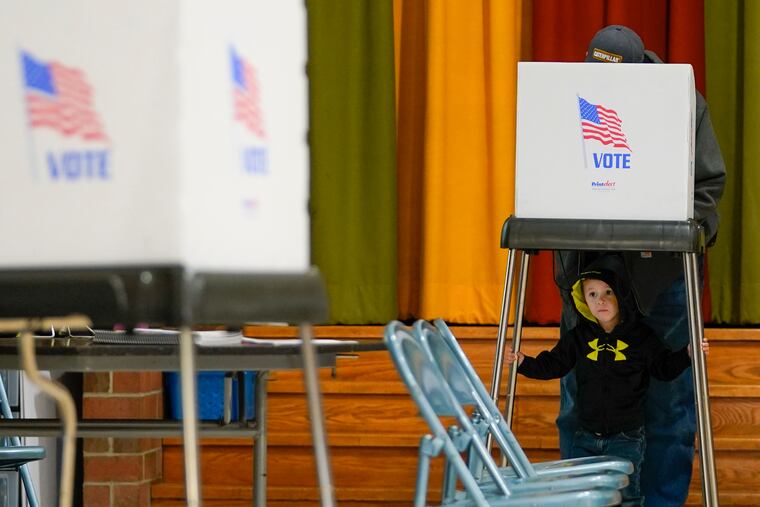 Jacob Lewis, 3, waits at a privacy booth as his grandfather, Robert Schroyer, fills out his ballot while voting at Sabillasville Elementary School, Nov. 8, 2022, in Sabillasville, Md. There were no digital intrusions known to have affected the counting of the U.S. midterm vote Wednesday after a tense Election Day in which officials were closely monitoring domestic and foreign threats.