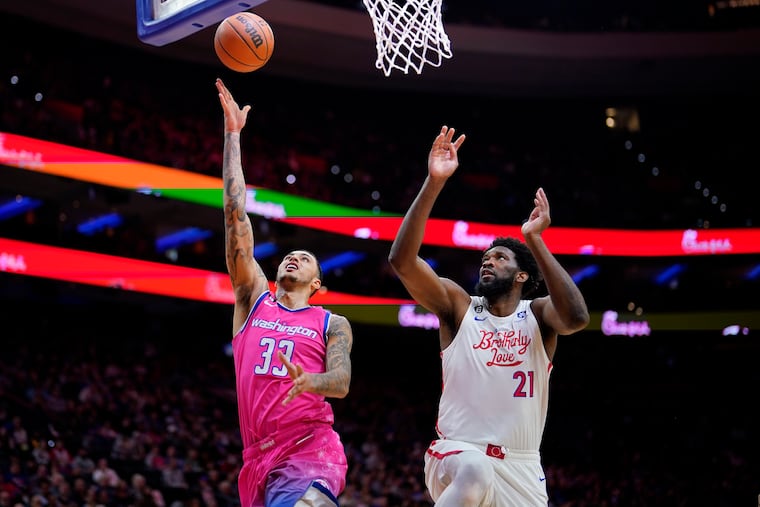 The Washington Wizards' Kyle Kuzma, left, goes up for a shot against the Sixers' Joel Embiid during an NBA game, Sunday, March 12, 2023, in Philadelphia.