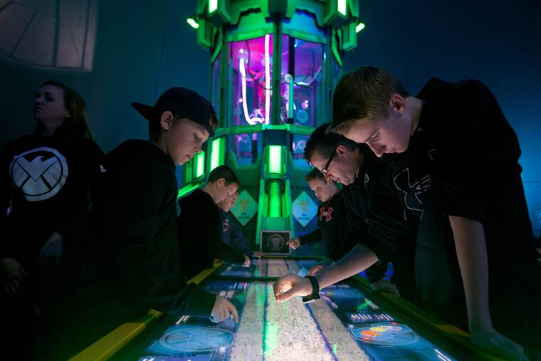 Recruits young and old are tasked to help piece together the Super Adaptoid with touch screen monitors. (File photo)