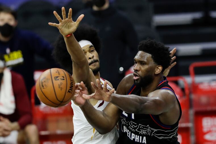 Sixers center Joel Embiid passes the basketball against Cleveland Cavaliers center Jarrett Allen on Saturday, February 27, 2021 in Philadelphia.