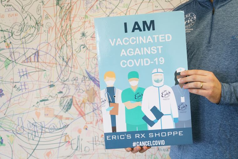 Marc Ost, co-Owner of Eric's Rx Shoppe, holds a sign that they made for children to hold and take photos with after they were vaccinated, in Horsham, Pa., Wednesday, February 2, 2022. The drawings on the wall of Eric's Rx Shoppe Vaccine Clinic in the background were done by children who had been vaccinated there.