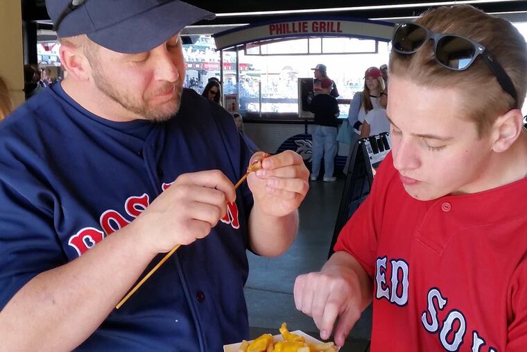 Matt, left, and Alex Caton, brothers, take a food break at the Lehigh Valley IronPigs baseball game. DAN MEYERS / For The Inquirer
