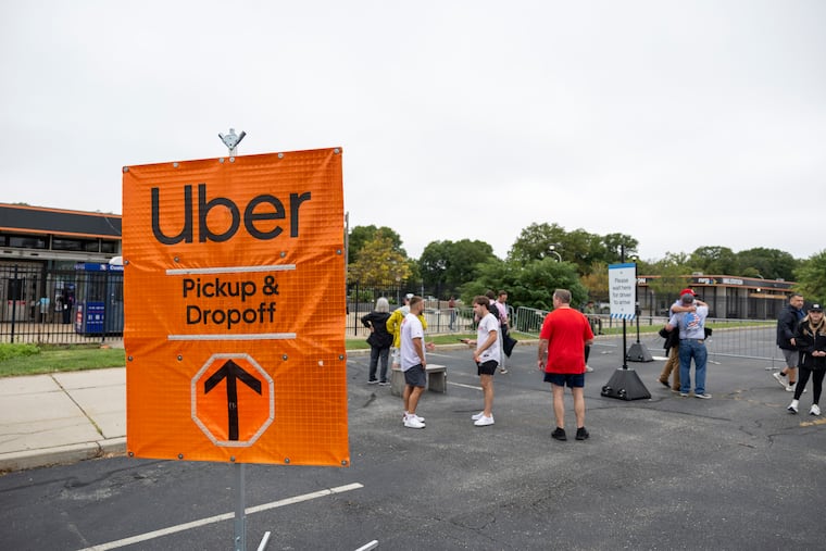 People wait for their Ubers at a designated pickup area in Lot T after the Phillies game on Wednesday. Most riders reported no issues, a stark difference from the scene in the lot earlier this summer.