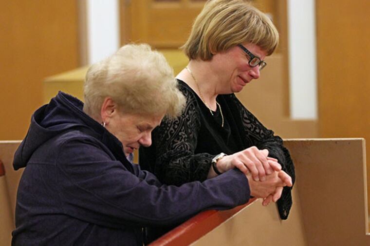 Catherine Rohland, right, holds onto her mother, Rose Walter, as they pray in the Church of St. William after holding a press conference asking the community for help in solving the murder of Donna Muller and her son Richard Muller in January of this year. ( MICHAEL BRYANT / Staff Photographer )