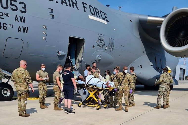 Medical support personnel help the Afghan mother, whose identity has been digitally obscured, with her family off an Air Force C-17 transport aircraft at Ramstein Air Base in Germany.