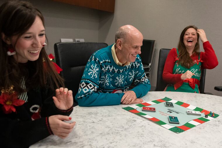 Donning "ugly" Christmas sweaters, sisters Cassie Collier (left) and Jacklyn Collier play their "Countdown to Christmas" Bundle board game with Bill Abbott, CEO of Crown Media Family Networks, parent of the Hallmark Channel, in his Midtown Manhattan office on Aug. 13.