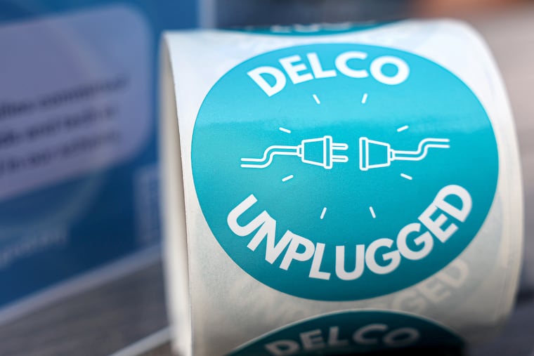 “Delco Unplugged” stickers and information about the organization rests on a table near Alex Becker, founder of Delco Unplugged, in Rose Valley on Sunday.