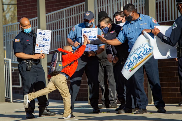 Devine Burton, 7, a first grader, high fives Camden firefighters and police officers on his arrival at H.B Wilson Elementary School. H.B Wilson School in Camden reopened for a select group of students returning to in-class learning on Monday. Students have been out of the classroom because of COVID-19 pandemic.