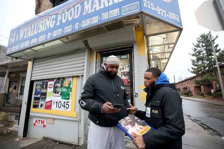 Robert Parker, left, and Brandon Jones, of the Philadelphia Anti-Drug Anti-Violence Network, talk outside of the 54 & Wyalusing Food Market. Two people were shot inside the store last night.