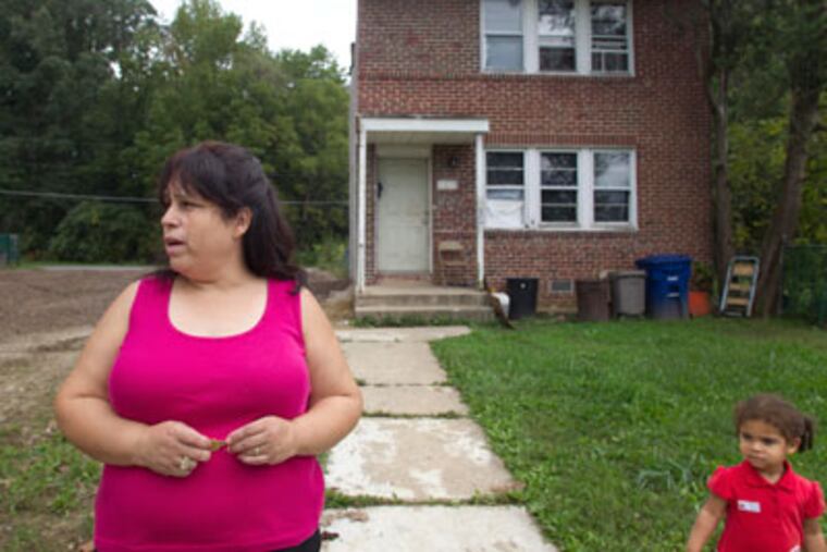Beatriz Cruz, who cares for her granddaughter, Alayah Collins (right), 2, has lived in Mount Holly Gardens for 20 years. The house adjacent to hers was removed this year. September 26, 2011. ( David M Warren / Staff Photographer )