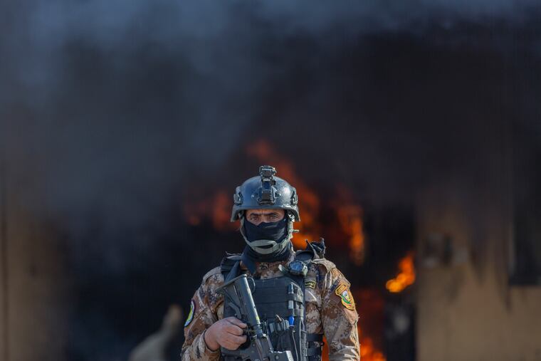 An Iraqi soldier stands guard in front of smoke rising from a fire set by pro-Iranian militiamen and their supporters in the U.S. embassy compound, Baghdad, Iraq, Wednesday, Jan. 1, 2020. U.S. troops fired tear gas on Wednesday as hundreds of Iran-backed militiamen and other protesters gathered outside the American Embassy in Baghdad for a second day and set fire to the roof of a reception area inside the compound.
