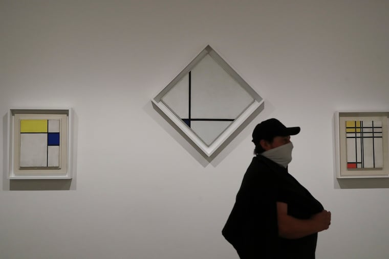 A visitor to the Philadelphia Museum of Art walks past the "Composition with Blue" (center), "Composition with Blue and Yellow" (left) and "Opposition of Lines, Red and Yellow" paintings by Dutch painter Piet Mondrian on Sunday.