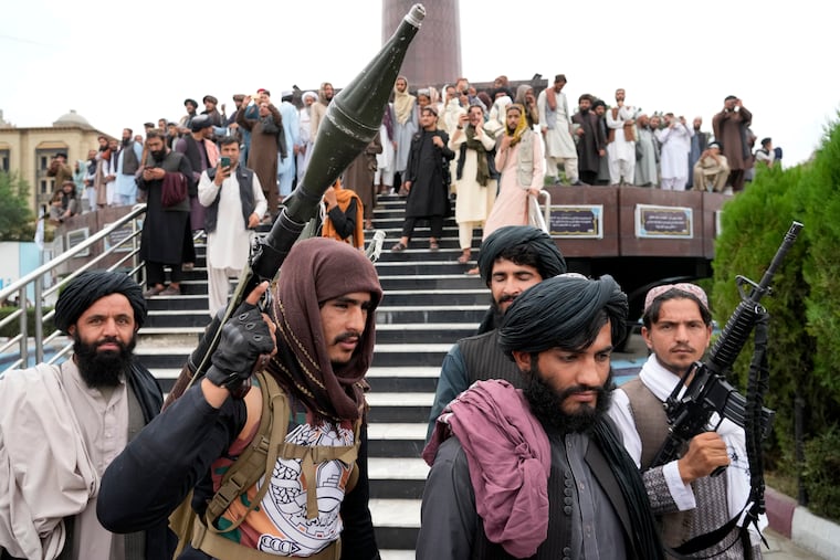 Taliban fighters celebrate one year since they seized the Afghan capital, Kabul, in front of the U.S. Embassy on Monday.