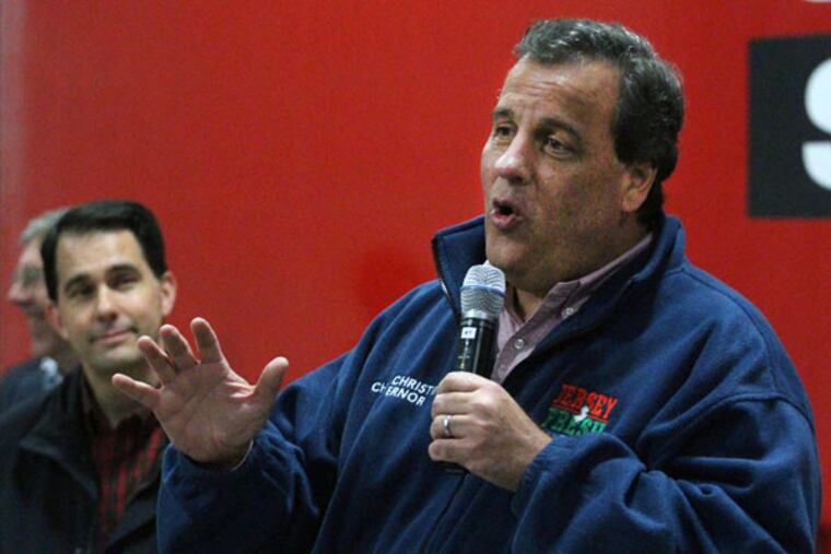 Gov. Chris Christie speaks with Wisconsin Gov. Scott Walker in the background as the two campaigned together at Wausau Supply in Schofield, Wis., on Friday, Oct. 31, 2014. (AP Photo/The Wausau Daily Herald, Dan Young)