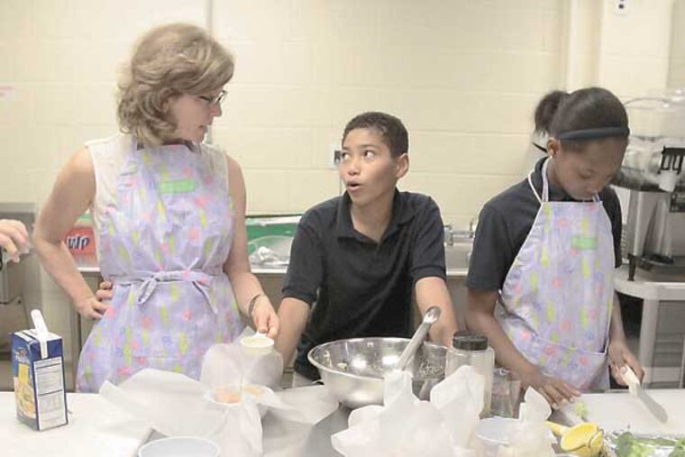 (L-R) Kimberly Luu, Kathy Luu, Maureen Fitzgerald, Nick Rodriguez, Nysirah Hall and Aneza Abalo while make poached chicken and roasted broccoli with students from Henry Lawton School in Phila. (Elizabeth Robertson/Staff Photographer)