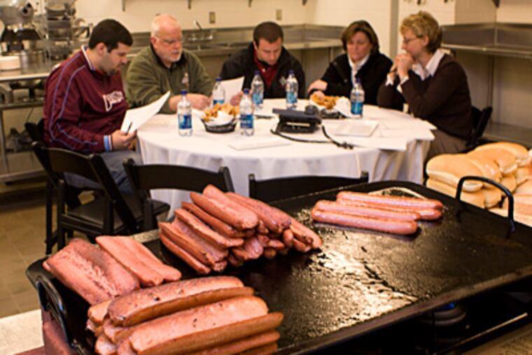 In the Aramark Kitchen at Citizens Bank Park, hot dogs sizzle on the grill as taste testers wait. Fans picked a winner: The South Philly. (Ed Hille / Staff Photographer)