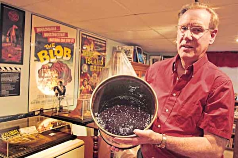 Wes Shank holds the bucket where he has his blob that is stored in his basement along with most of his collectibles. The annual blobfest, a weekend-long celebration of the sci fi classic the Blob, will be held in Phoeniville where the movie was shot in the 1950s. We profile Wes Shank, of Broomall, a movie memorabilia collector and the owner of the red goop taken on Tuesday, July 9,2013. ( RON CORTES / Staff Photographer ).