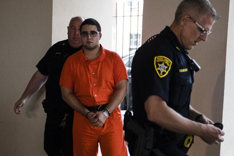 A law enforcement official escorts Cosmo DiNardo to a vehicle in Doylestown last summer.