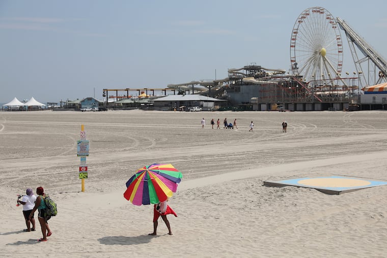 A woman carries an umbrella across the beach in Wildwood in July; this should be a spectacular weekend at the Shore.