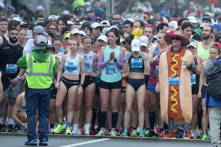 Runners gather, including a person dressed in a hot dog costume holding a margarita, at the starting line of the 2024 Broad Street Run.