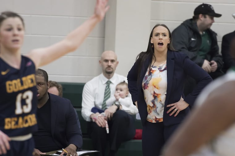 Wilmington University men's basketball coach Dan Burke, with daughter Julianna on his lap, watching his wife, Goldey Beacom women's coach Bethann Burke. coach on Saturday.