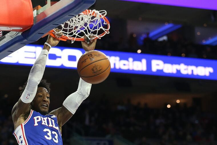Robert Covington dunks over the Raptors’ Kyle Lowry, right, as Joel Embiid watches in the second quarter.