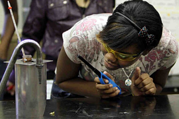 Mjaan McIvor, 15, a Central High School biology student, checks on the progress of an experiment in which the caloric content of a typical school lunch was determined by burning ingredients. (Laurence Kesterson/Staff)