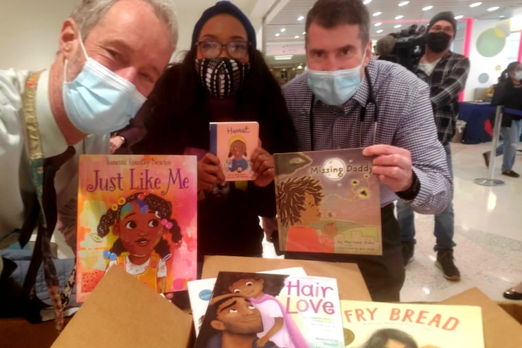 St. Christopher's pediatricians Hans Kersten (left) and Dan Taylor (right) with Harriett's Bookshop owner Jeannine Cook and some of the books in the fund-raising Reading Tournament for the Reach Out and Read Program. Taylor told recent medical school graduates that they need to get out of the usual medical lane and consider all their patients' needs.