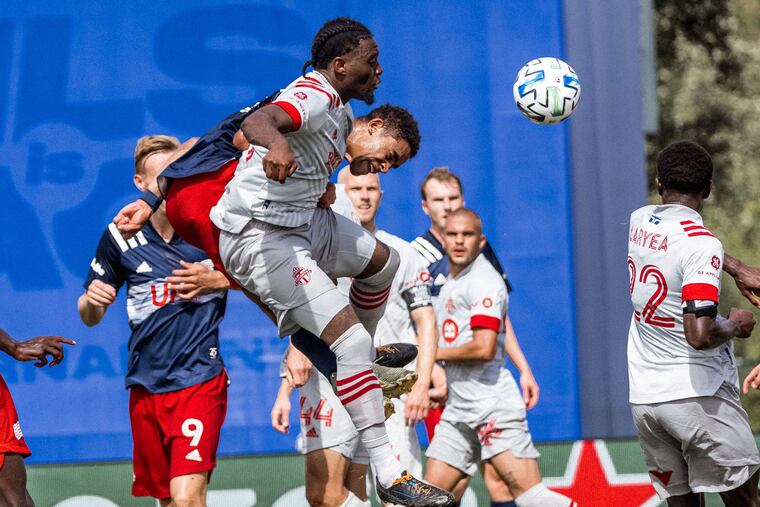 Toronto FC and New England Revolution players jousting for a ball in the air during Tuesday morning's game.