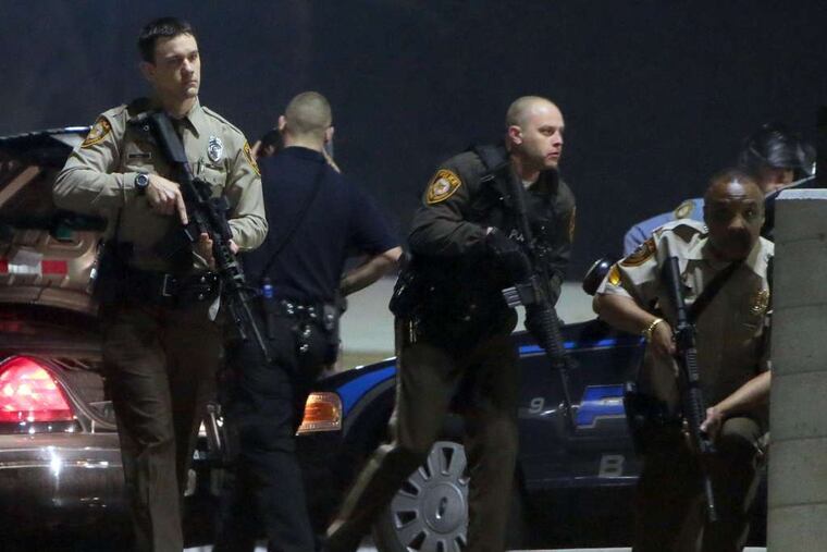 Police mobilize in the parking lot of the Ferguson police station after two officers guarding the building's front were shot. No suspects were in custody Thursday.