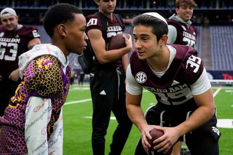 Texas A&M wide receiver Sam Salz gives instruction to a child from the DePelchin Children’s Center during a drill after practice on Dec. 26, 2023.
