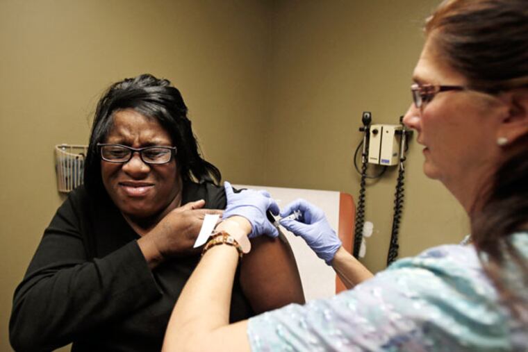 In this 2013 photo, nurse Debbie Smerk (right) administers a flu shot to Pamela Black at MetroHealth in Cleveland.