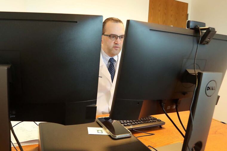Dr. Raed Azzam, an epileptologist with the Cleveland Clinic Neurological Institute, talks with a patient during a telemedicine appointment at his office in March.
