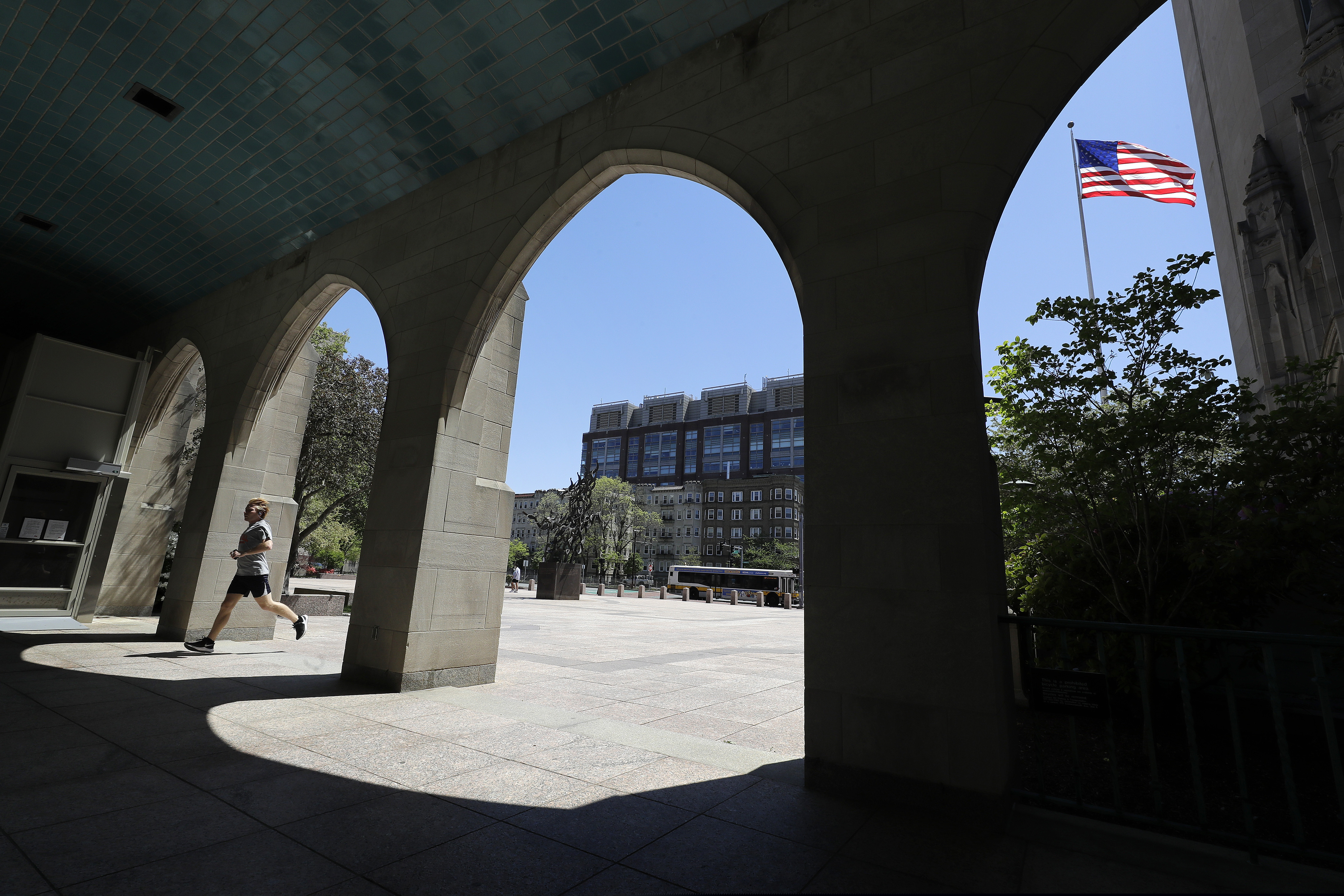 A runner passes through an arch on the campus of Boston University on May 20, 2020. COVID-19 has disrupted the plans of an estimated 3 million returning college students.