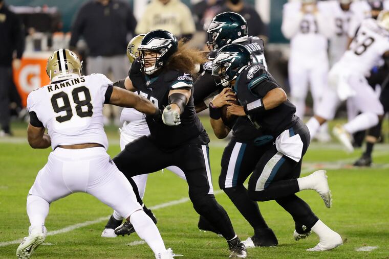 Eagles quarterback Jalen Hurts scrambles with the football as offensive guard Isaac Seumalo blocks New Orleans Saints defensive tackle Sheldon Rankins.