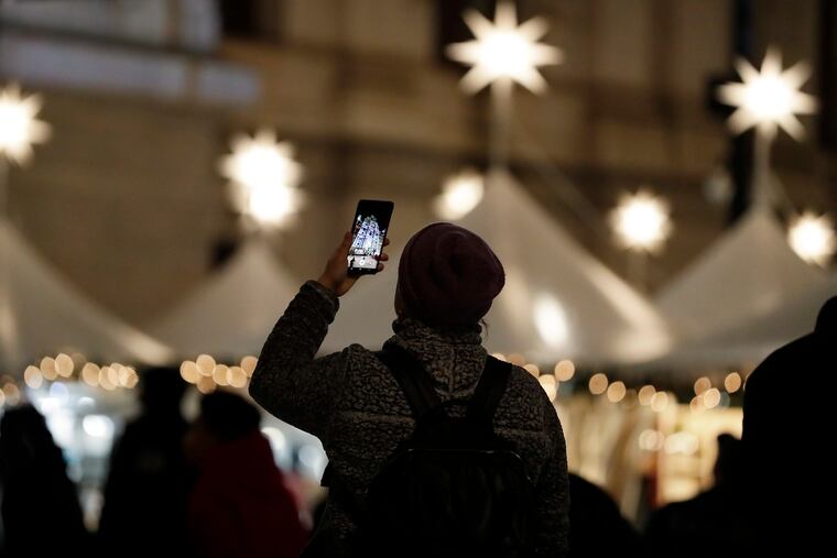 A visitor to Dilworth Park at City Hall records the Deck the Hall Holiday Light Show on Tuesday. Enjoy the season, but take some basic precautions to boost your chances of avoiding colds and flu.