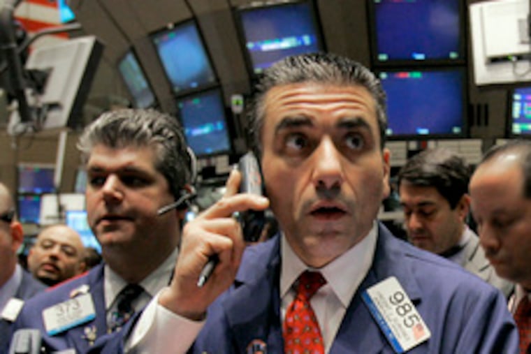 Trader Vincent Quinones (center) stands on the floor of the New York Stock Exchange. Stocks had a rough ride after the Fed announced a key interest-rate cut, but they ended on the rise.