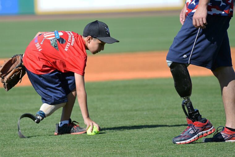 Adrian Grajeda fields the ball with a wounded warrior nearby. (Photo: Wounded Warrior Amputee Softball Team)