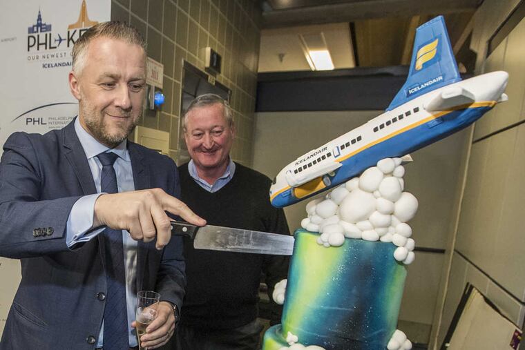 Icelandair CEO Birkir Holm Guonason, left, cuts a cake to celebrate Icelandair’s inaugural flight to Philadelphia as Mayor Philadelphia James Kenney, right, look on.