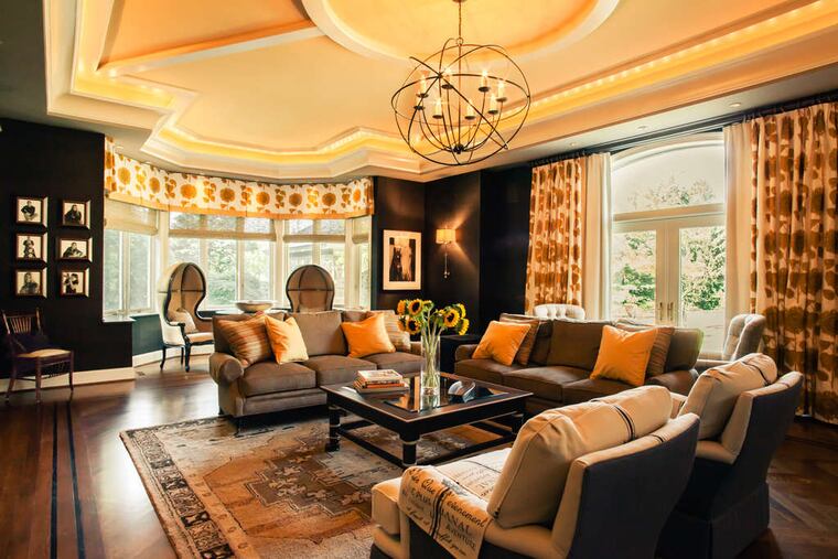 Designer Linda Dooney made a large Villanova family room feel cozy and inviting by covering the walls in charcoal-gray, a nearly-black backdrop.