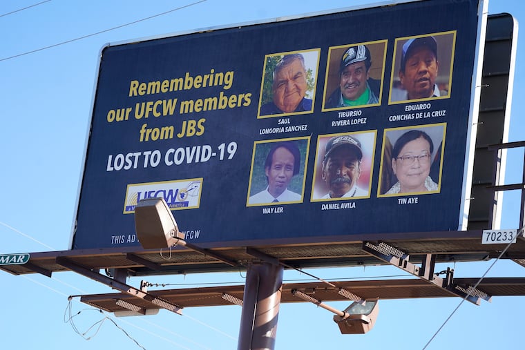 A billboard with the images of the six employees who died of COVID-19 while employed at the JBS meatpacking plant stands across from the plant along Highway 85, Monday, Oct. 12, 2020, north of Greeley, Colo. (AP Photo/David Zalubowski)