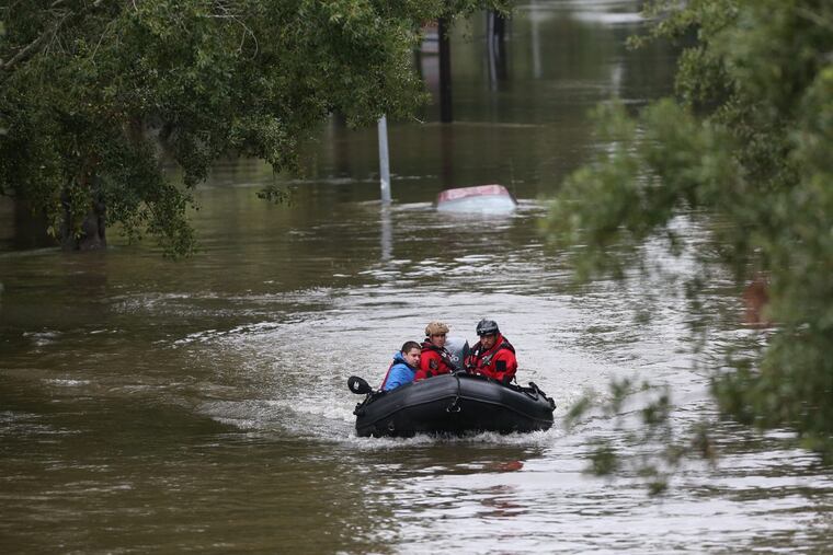 Daniel Gross, 15, is rescued by Houston Police after he was left stranded on top of his car in Houston on Sunday, Aug. 27, 2017, as Tropical Storm Harvey continues to cause major flooding throughout Southeast Texas. (Robert Gauthier/Los Angeles Times/TNS)