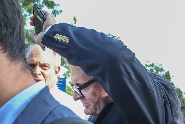 Peter Bistrian, a former Chadds Ford financial adviser, tries to hide his face from photographers as he leaves federal court in Philadelphia on Tuesday, July 9, 2019.